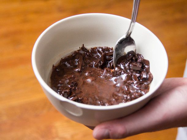 Author stirring the partially melted chopped chocolate with the coconut oil and corn syrup in a small bowl.