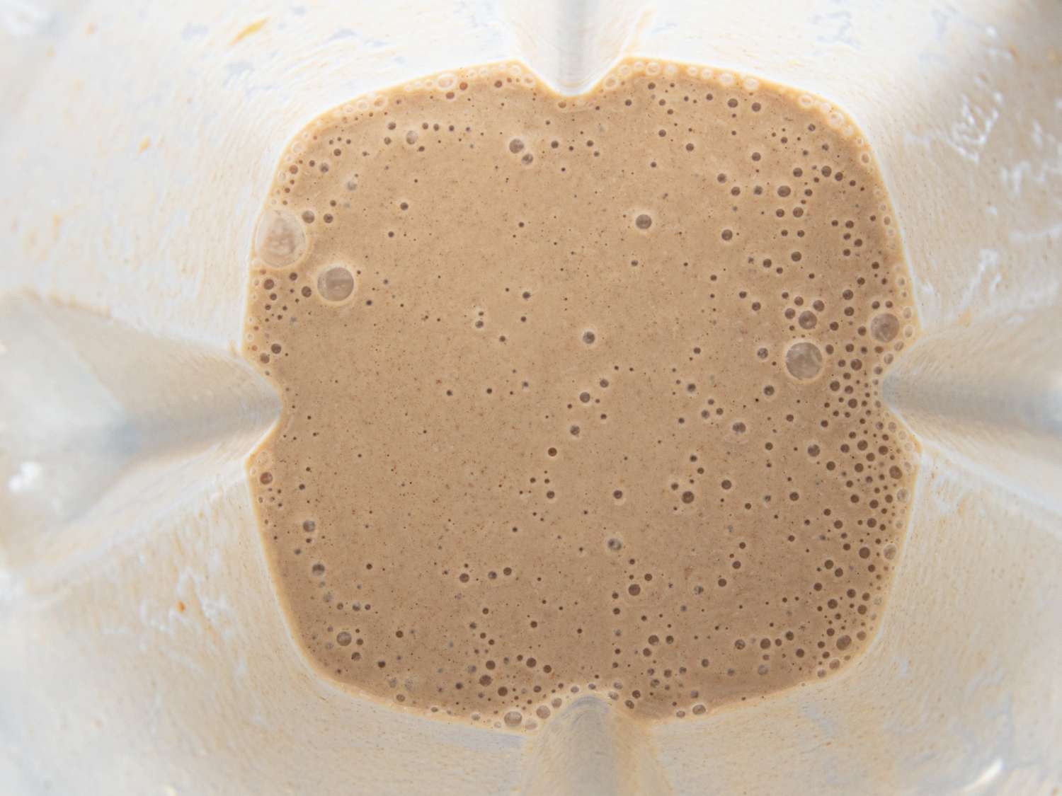 Banana date smoothie in a blender top view of blended mixture with bubbles
