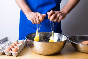 person cracking eggs into bowl