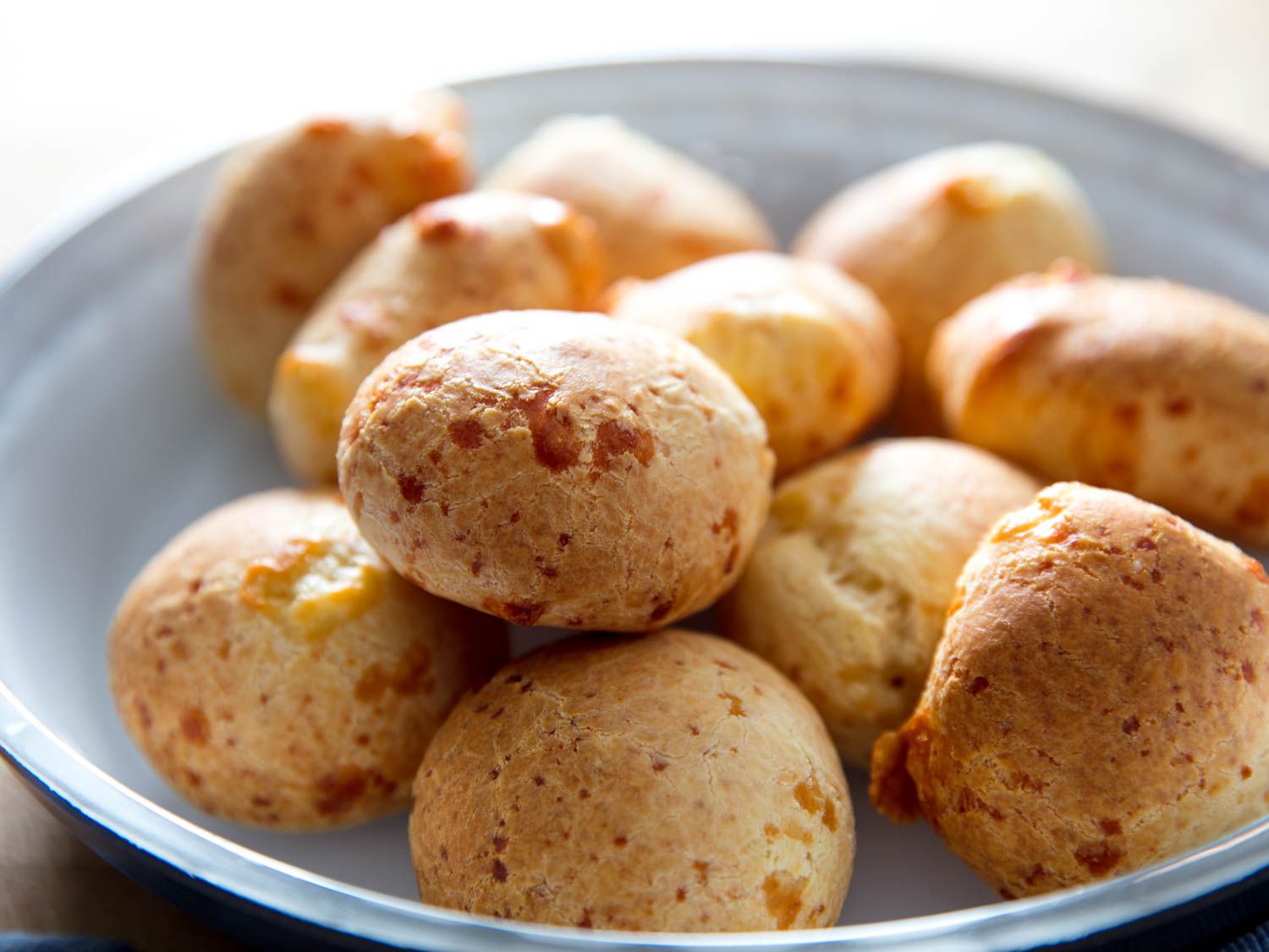 Side view of Cuñapes/Pão de Queijo (South American Cheesy Bread) on a blue plate