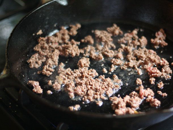 Browning ground beef in a cast iron skillet.