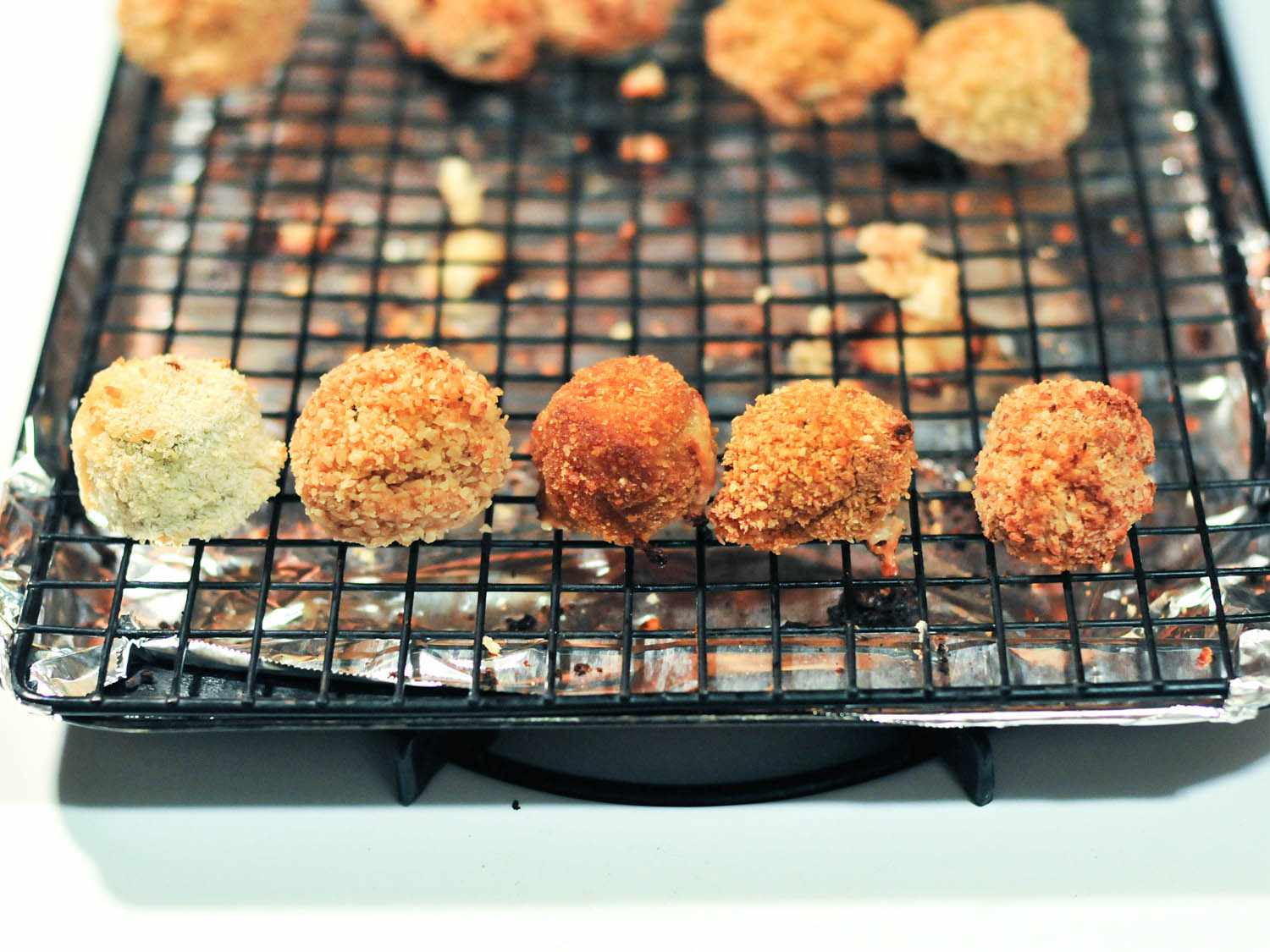 Baked jalapeno poppers resting on a wire rack in a rimmed baking sheet.