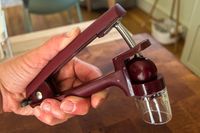 A person about to pit a cherry with the OXO cherry pitter