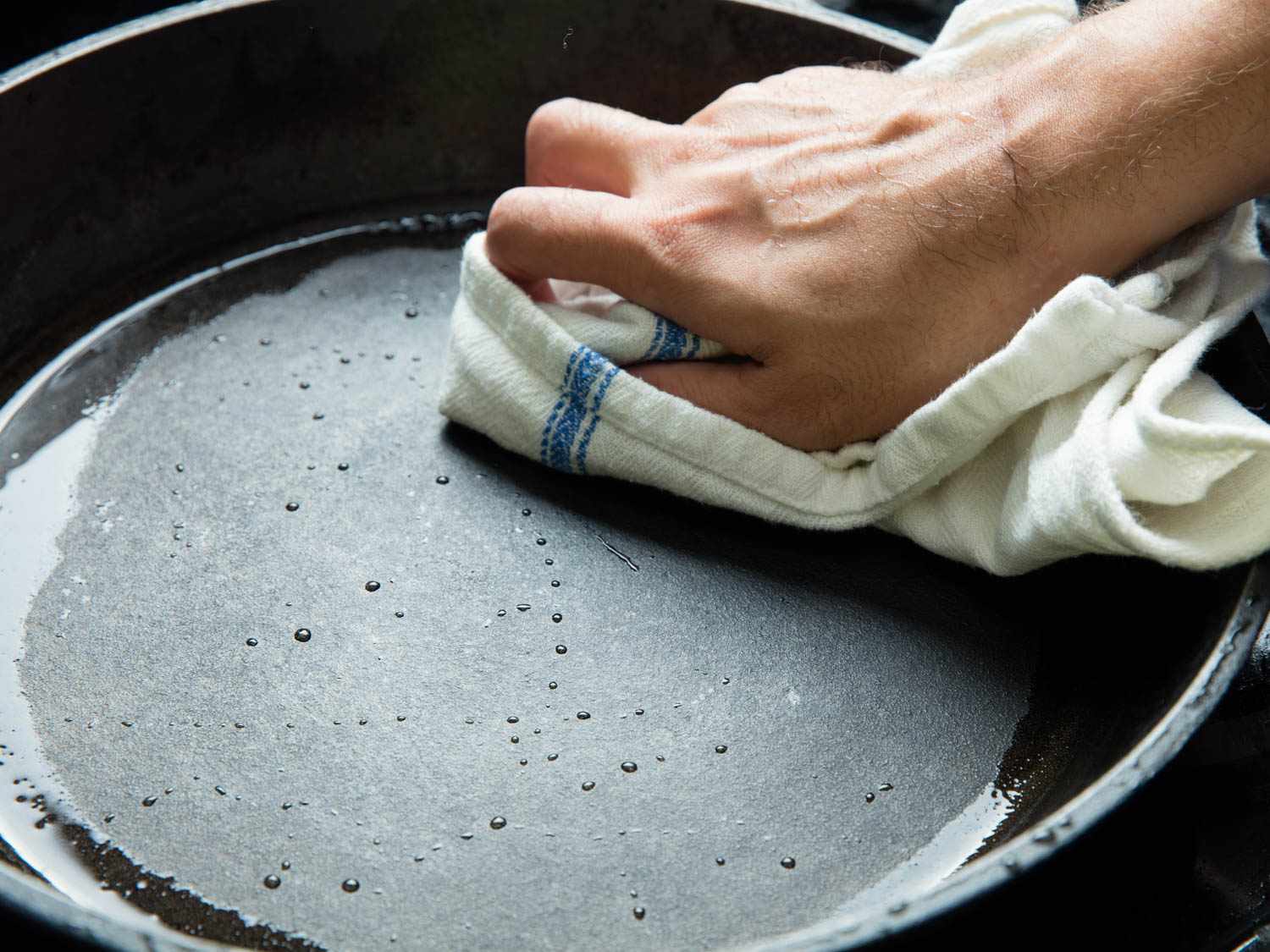 Drying a cast iron pan thoroughly after washing.