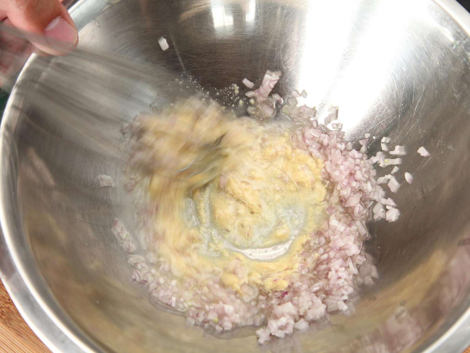 Author whisks together Dijon, shallot, and vinegar in the mixing bowl.
