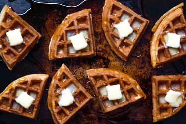 Buttermilk Vanilla waffles on a baking sheet topped with melting butter.