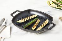 The Victoria Cast Iron Square Grill Pan on a table with grilled zucchini inside the pan. 