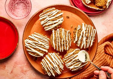Gingerbread muffins with icing served on a plate with a hand applying more icing using a spoon