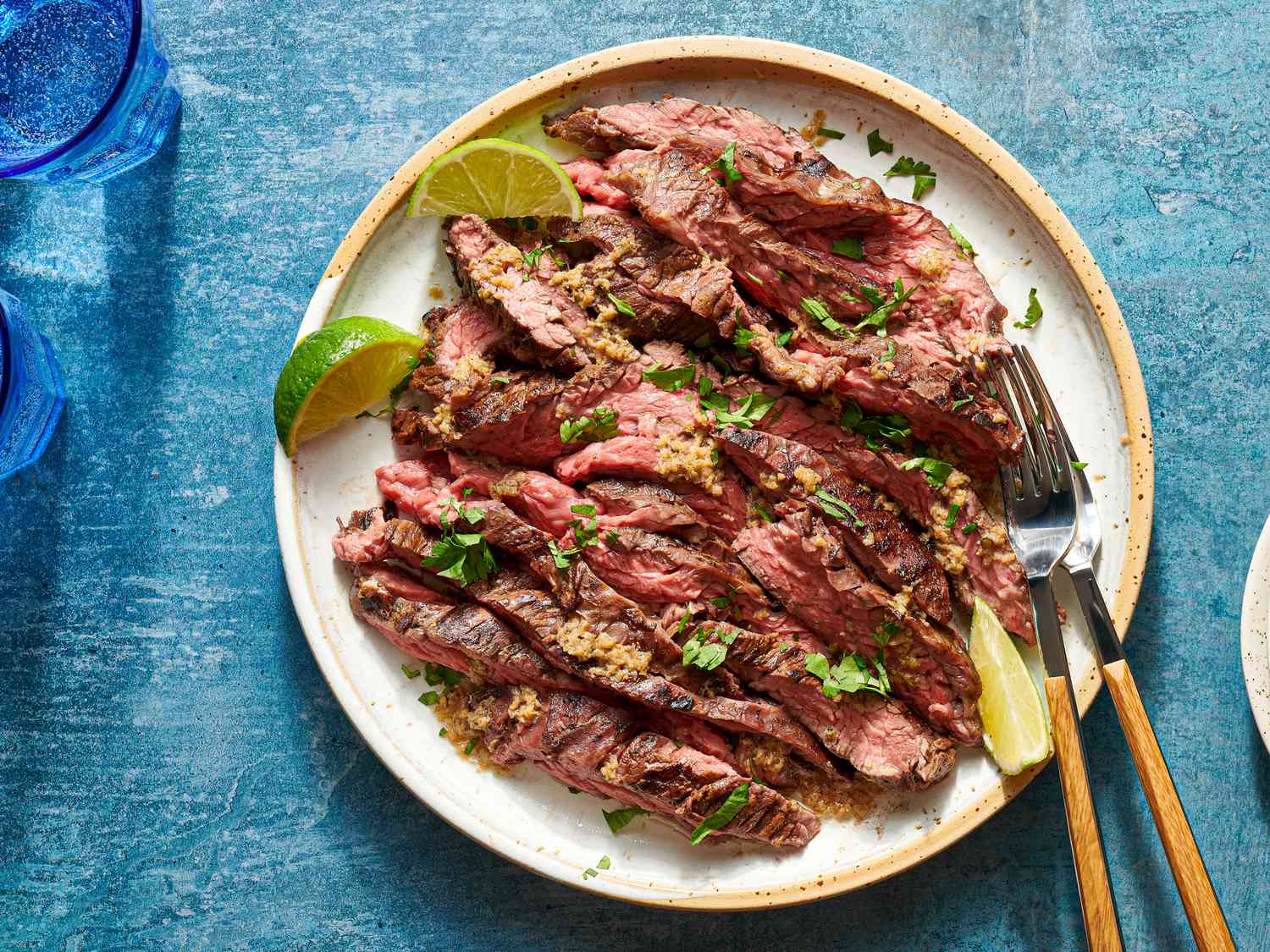Grilled skirt steak with mojo marinade served on a plate with lime wedges