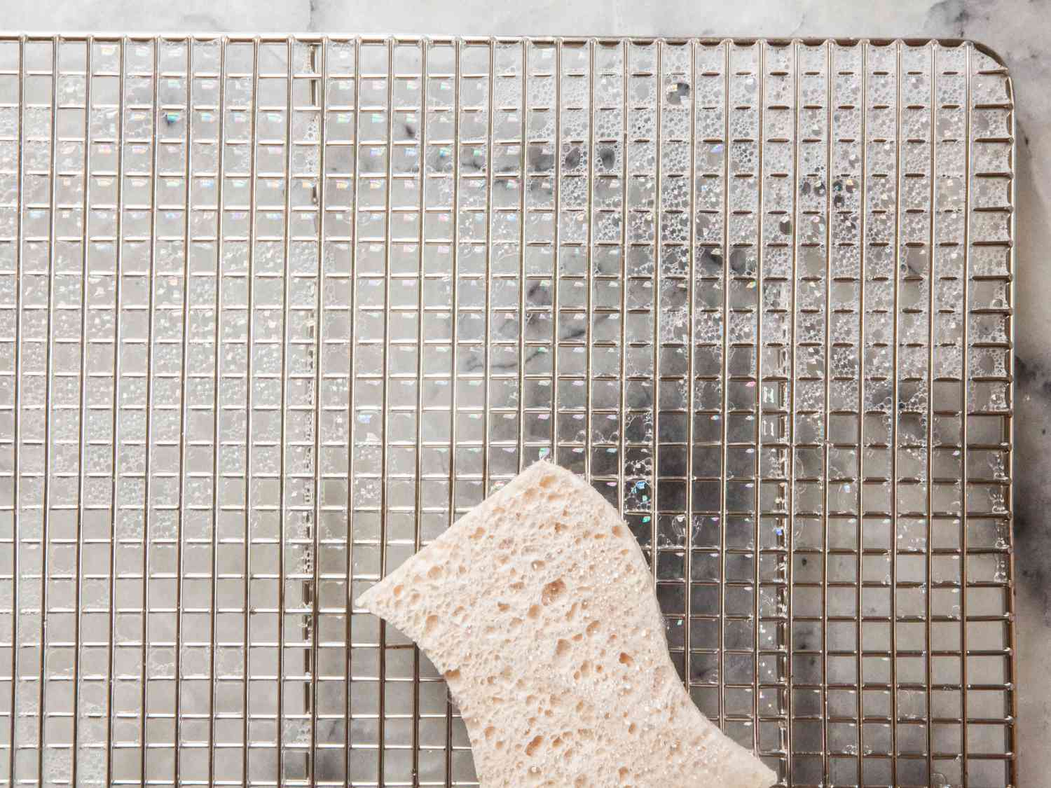 a sponge cleaning a wire cooling rack
