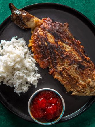 tortang talong on a black plate with white rice and banana ketchup