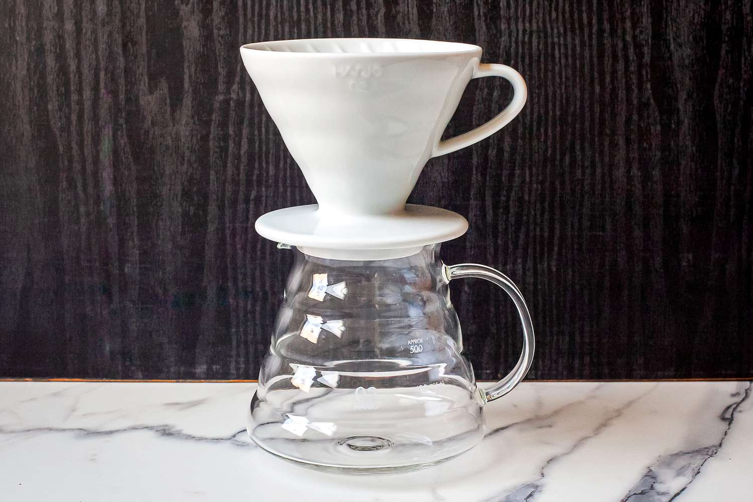 A ceramic coffee dripper positioned on a glass carafe