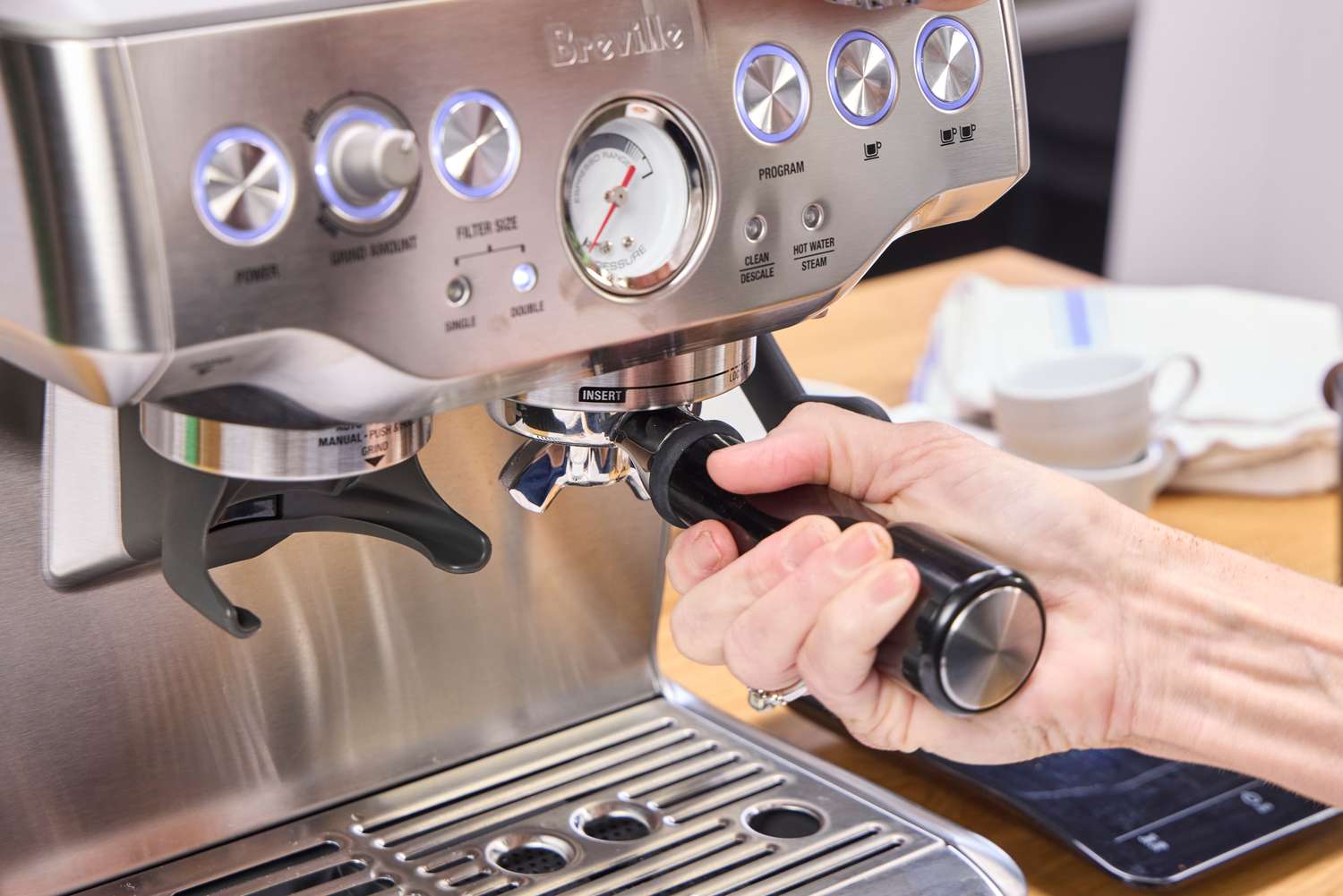 A person brews espresso in the Breville The Barista Express Espresso Machine