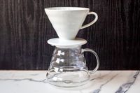 A ceramic coffee dripper positioned on a glass carafe