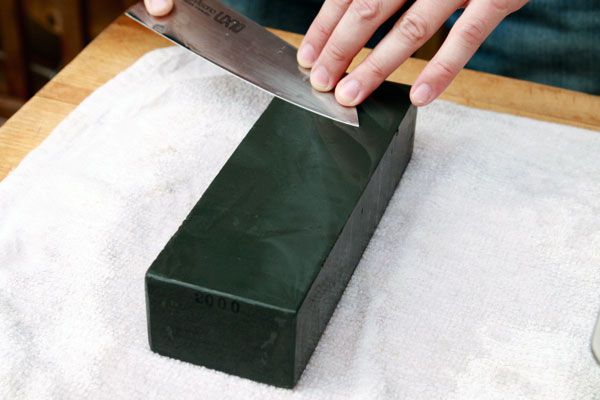 Hands sharpening a knife on a lower grit whetstone