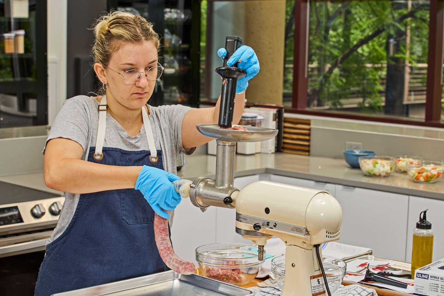 Person pushing meat in KitchenAid KSMMGA Metal Food Grinder Attachment to make sausage