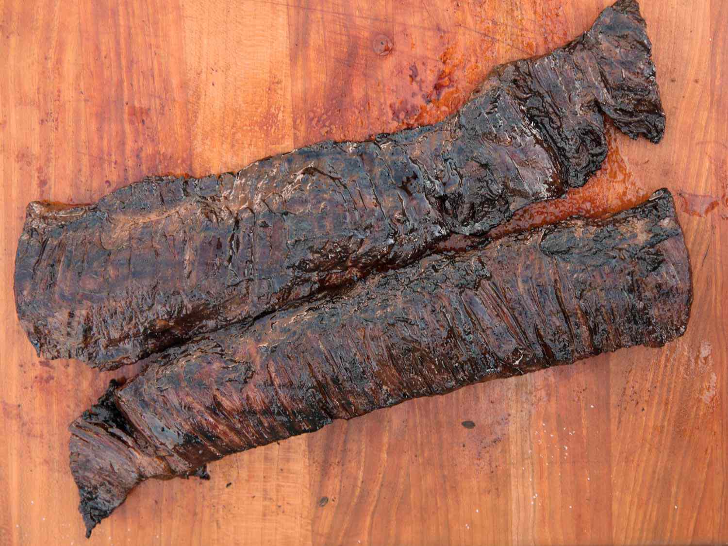Two black diamond-marinated skirt steaks, arranged on a cutting board.