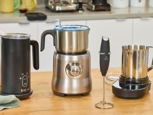 Four milk frothers on a kitchen countertop.