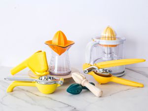 Various citrus juicers on a marble countertop. 