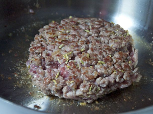 A patty of the sausage mixture is par-cooked in a skillet.