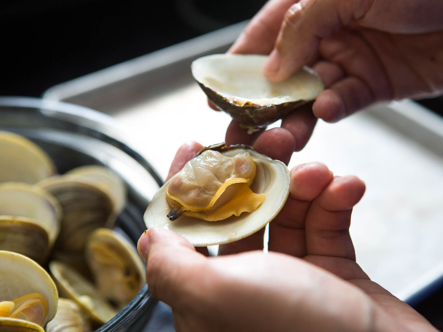 The top shell of a cooked clam being pried off