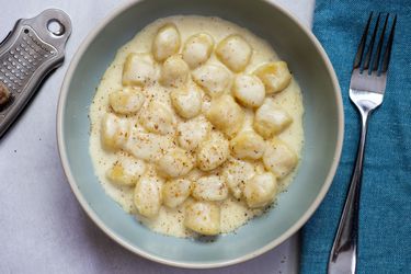 Gnocchi in a cheese sauce resting in a blue bowl