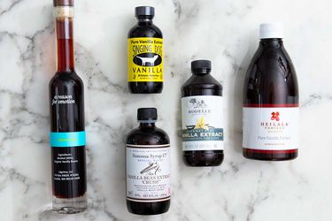 An assortment of vanilla extract bottles on a marble background.