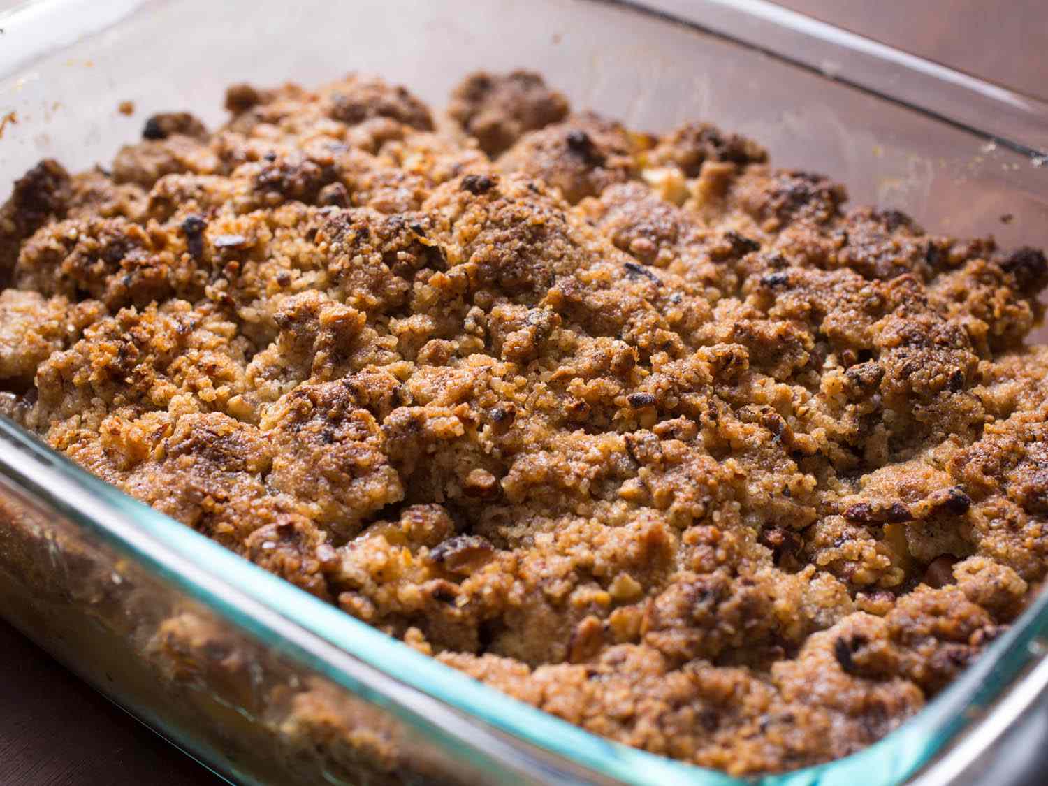 A glass baking dish of apple crisp with a pecan crumble topping.