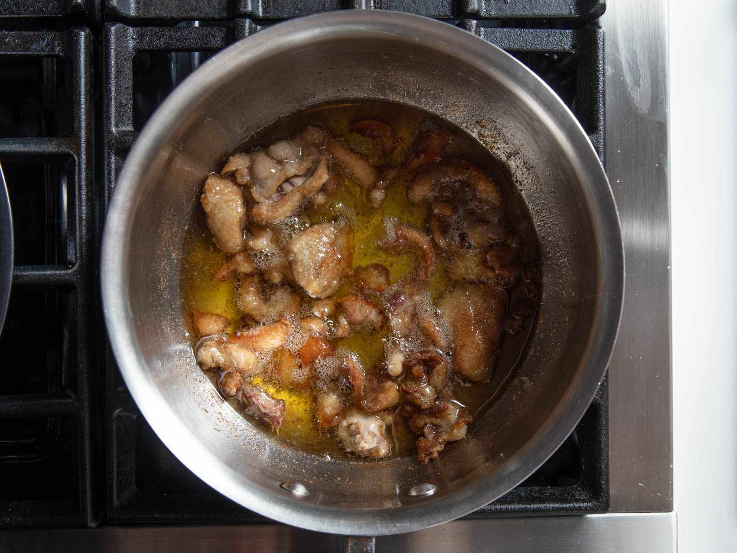 Overhead of saucepan with rendered duck fat and skin .