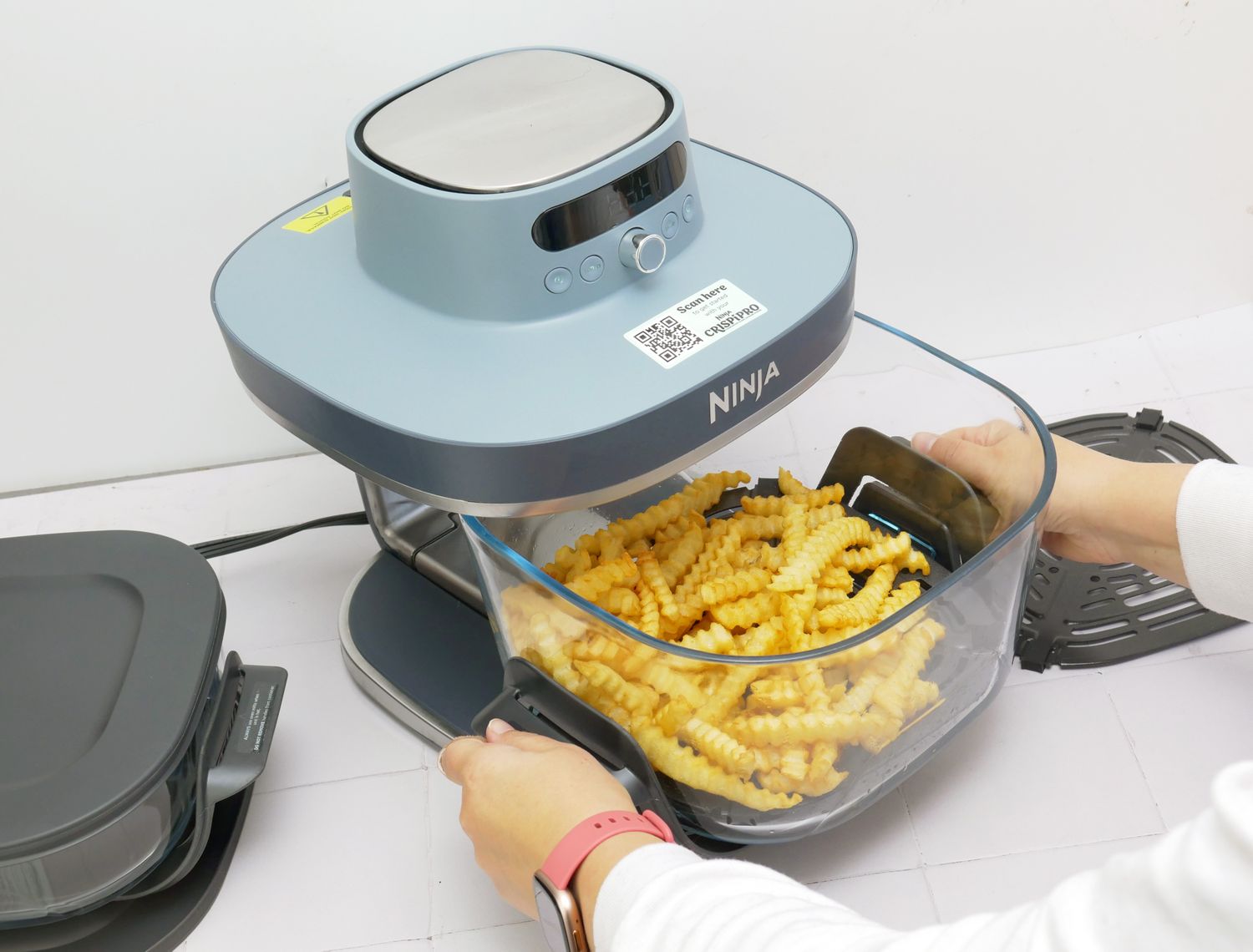  a person removing the basket from the ninja crispi pro air fryer