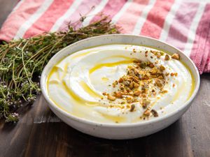 whipped feta in a white bowl and garnished with olive oil and crushed nuts