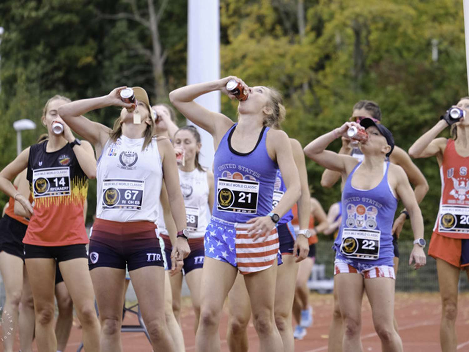 Athletes on a track drinking from bottles during a race or event
