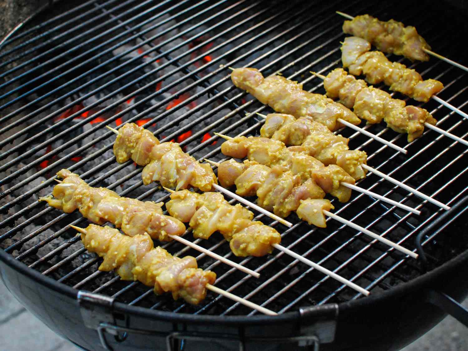 Skewered coconut milk and curry chicken on a grill.