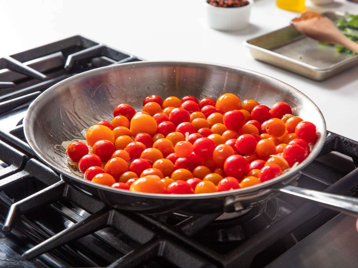 Shaking skillet to arrange cherry tomatoes in a single layer.