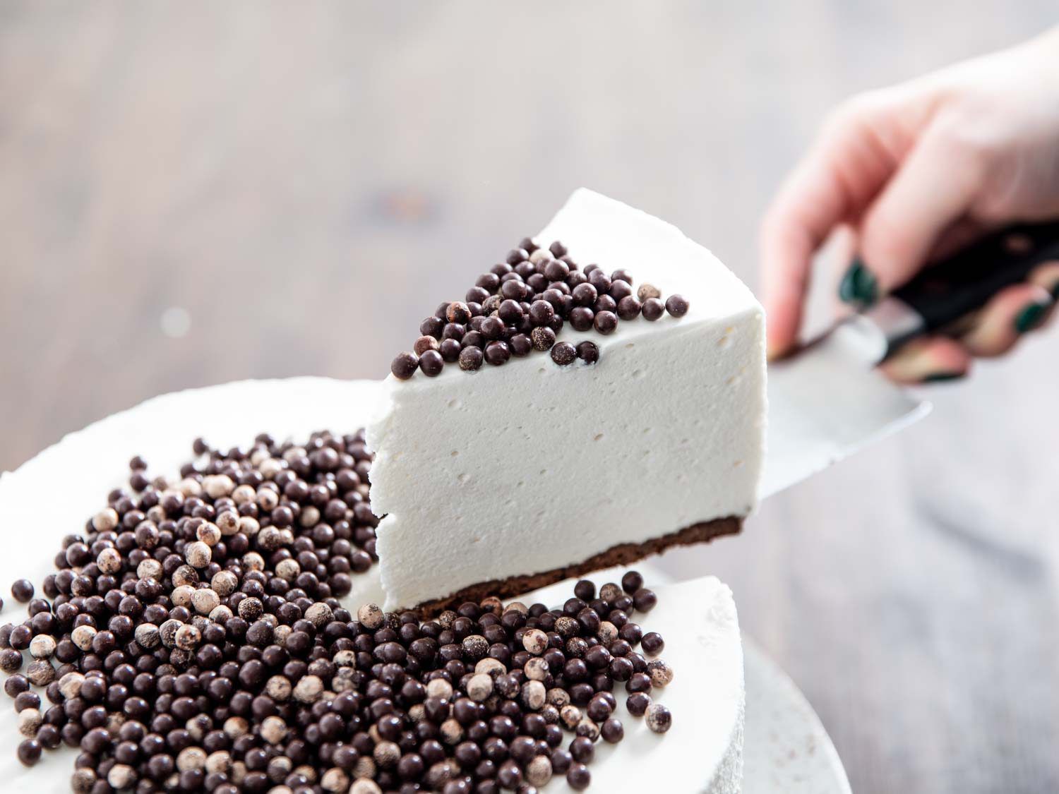 Lifting a slice of fluffy no-bake cheesecake from the whole cake.