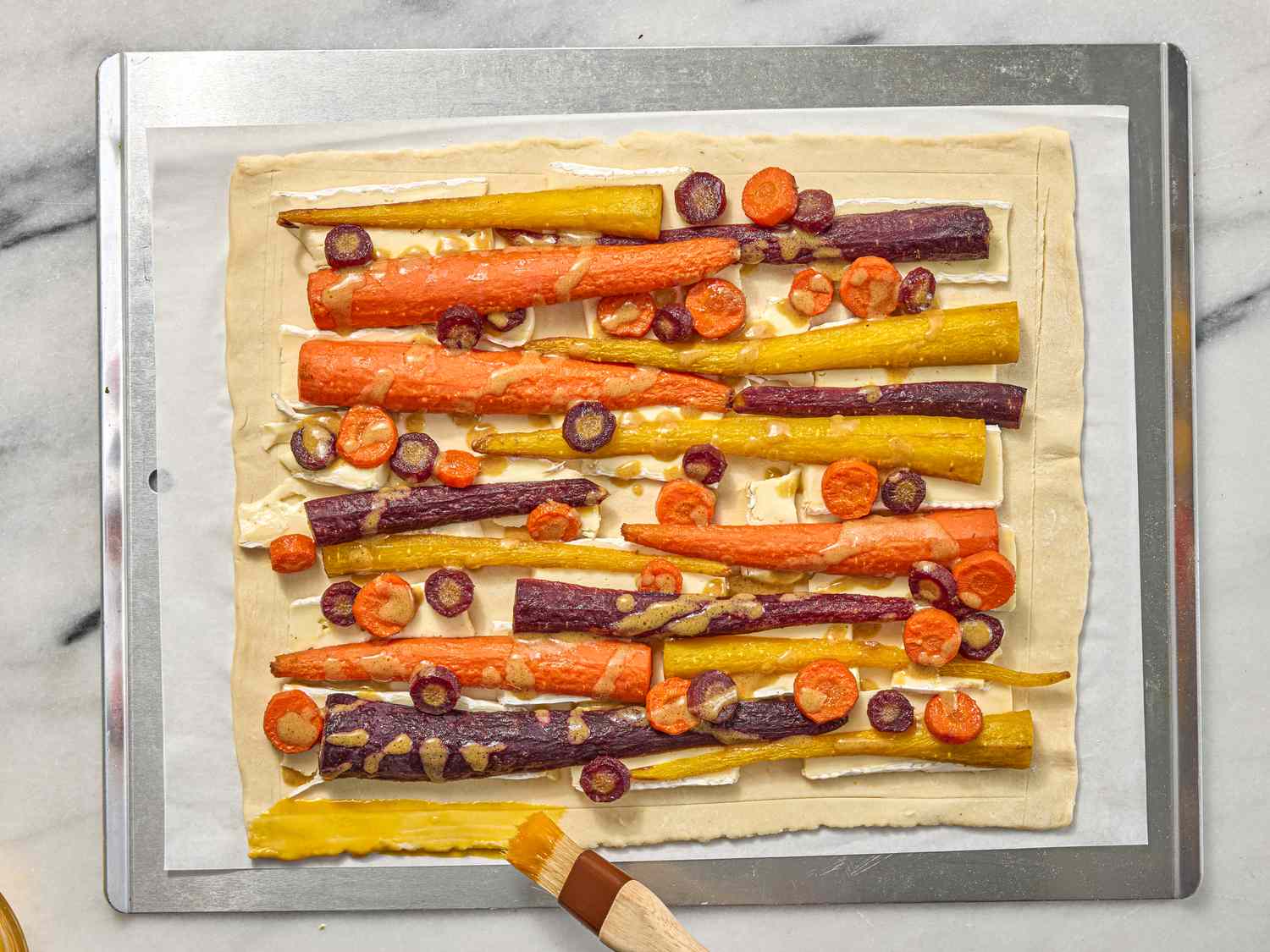 brushing the crust of a carrot tart on a sheetpan 