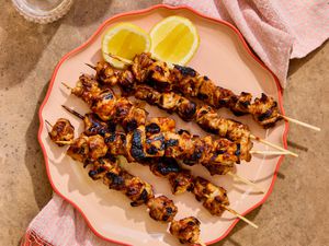 Honey harissa glazed chicken skewers on a platter with lemon slices