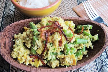Balinese chicken lawar served in a wooden bowl beside a bowl of white rice