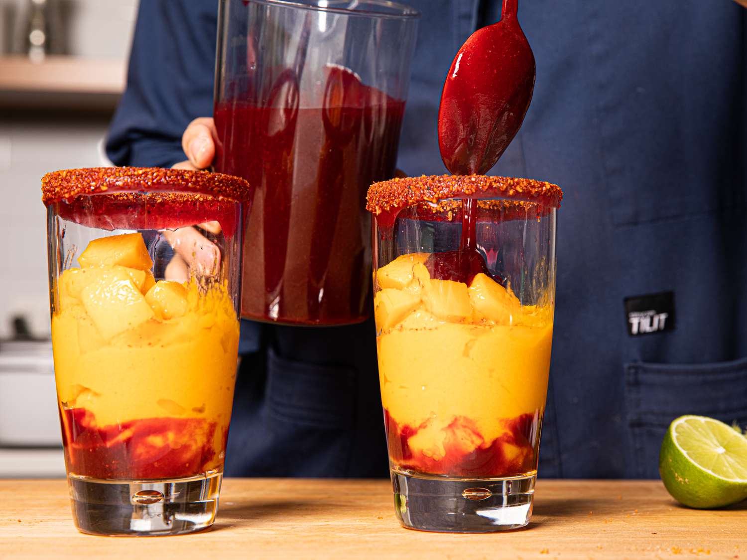 Adding chamoy to the middle layer of the mangonadas.