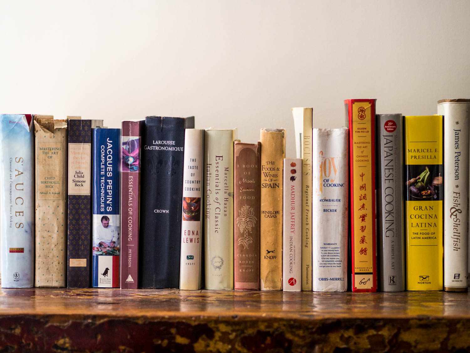 A wooden shelf full of essential cookbooks