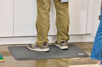 A person stands on the WellnessMats Original Anti-Fatigue Floor Mat