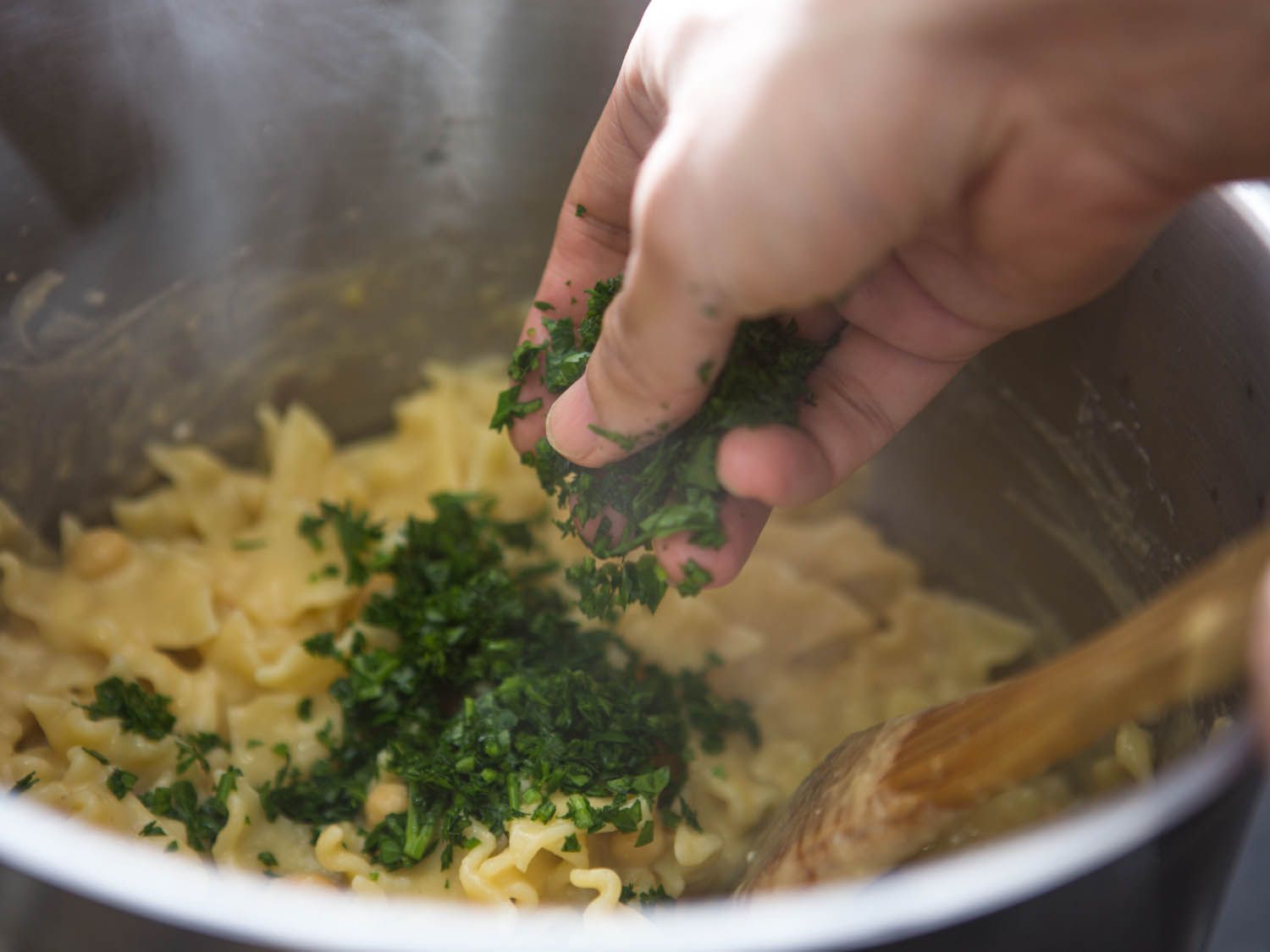Parsley is added to the sauced pasta.