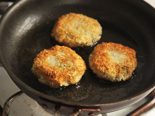 Chickpea fritters, fried and golden brown, in a skillet with hot oil.