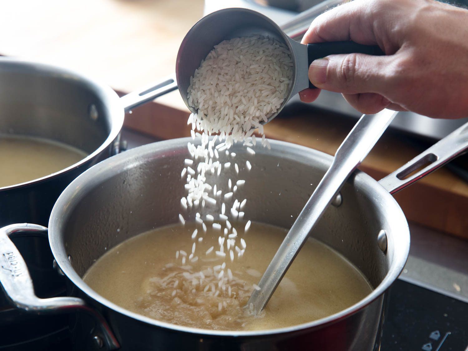 Adding rice to a pot of homemade avgolemeno soup.