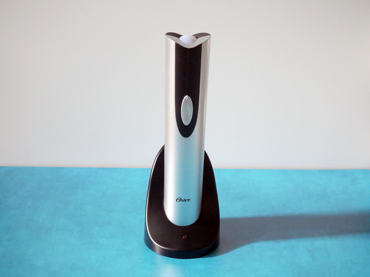 oster electric corkscrew in stand on blue countertop