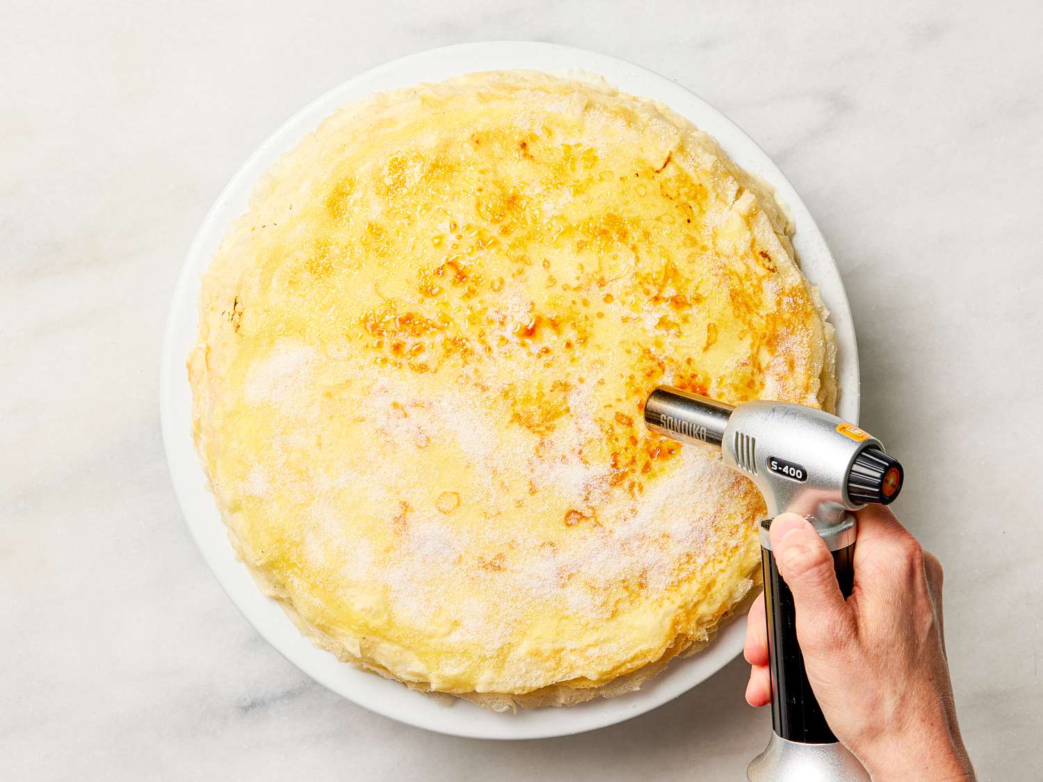 Overhead view of torching the sugar on top of the cake