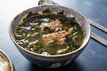 A bowl of Korean Miyeok-Guk, showing simmered seaweed, chunks of tender meat, and a light broth.