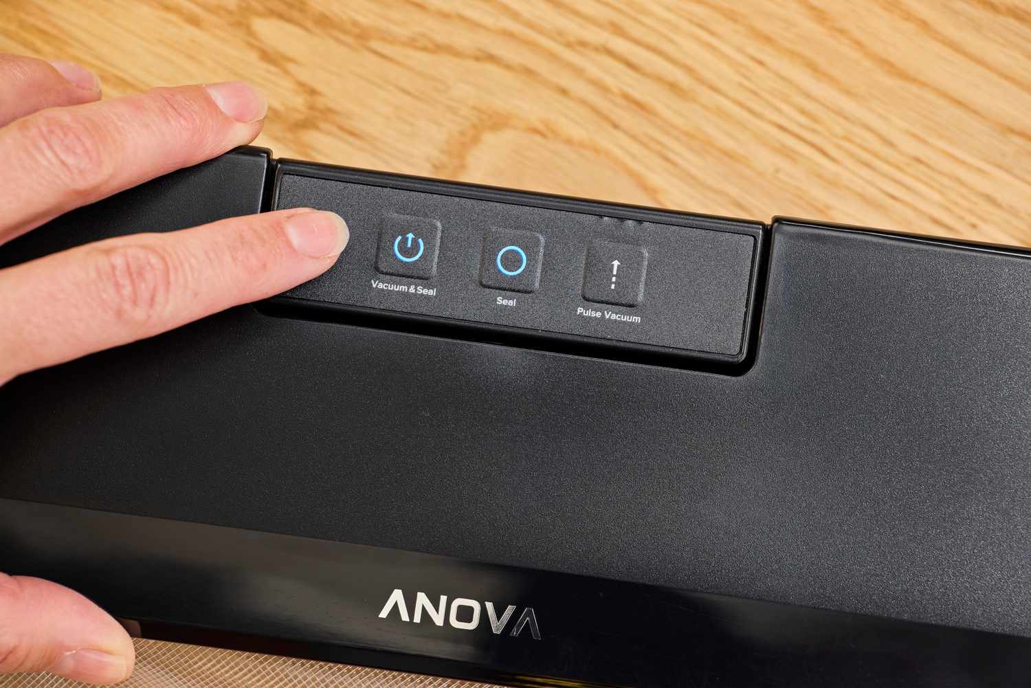 A person presses a button on the Anova Precision Sous Vide Vacuum Sealer