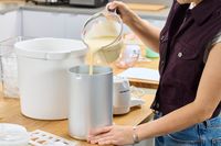 A person pouring liquid into the Hamilton Beach Automatic Ice Cream Maker