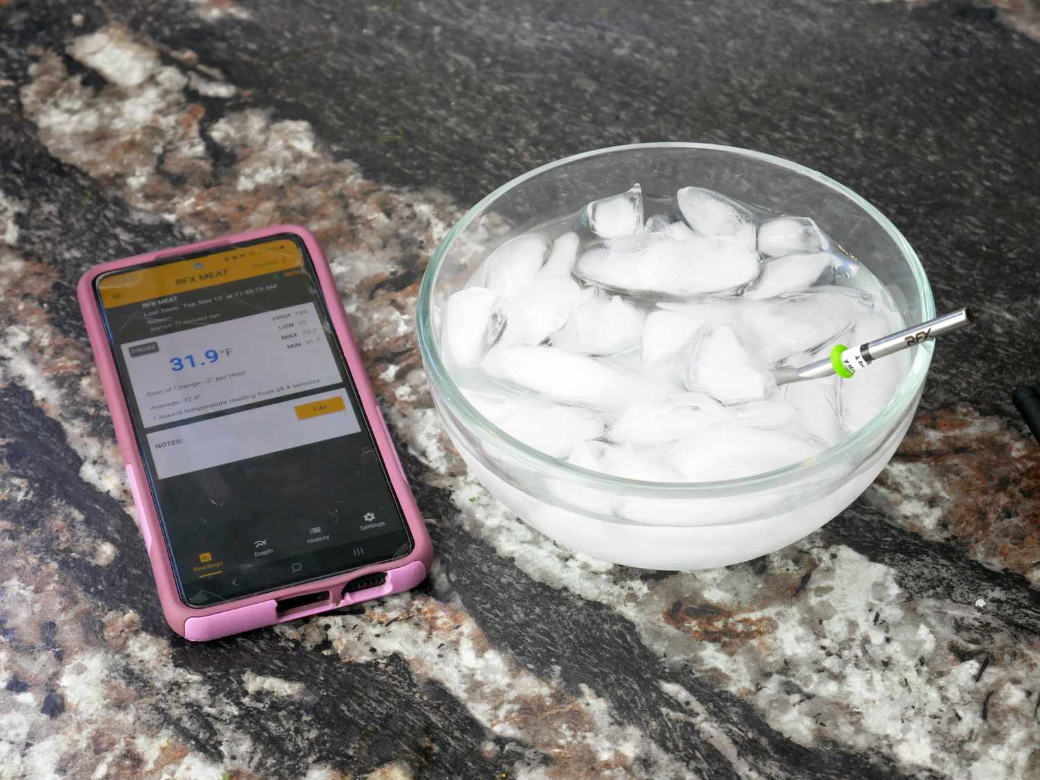 a phone displaying the temperature reading of the probe which is in an ice bath